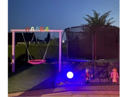 Schaukel und Trampolin in einem Garten bei Nacht