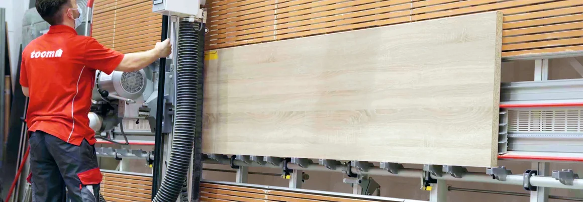 Person schneidet Holzplatte mit Maschine zu