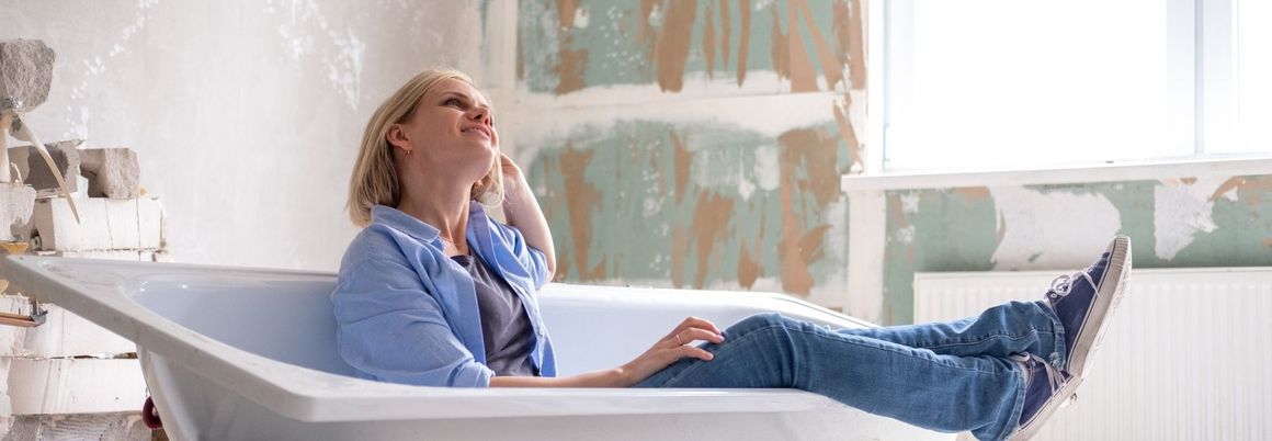 Frau liegt in einer Badewanne während um sie herum renoviert wird 