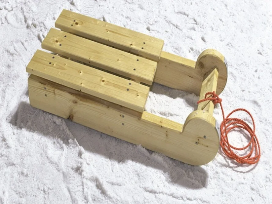 Ein einfacher Holzschlitten auf frischem Schnee.