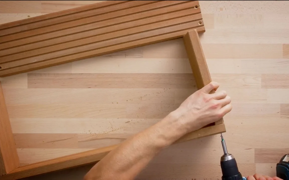 Person verschraubt Holzbretter mit Akkuschrauber.