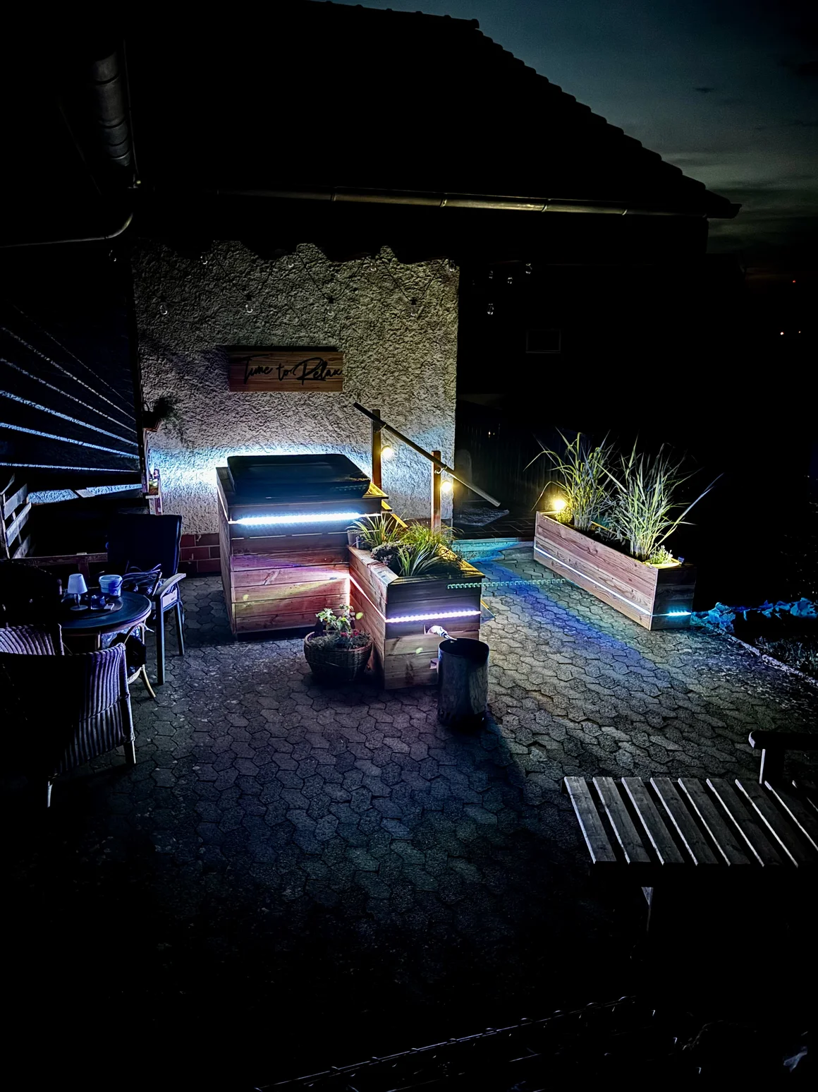 Stimmungsvoll beleuchtete Terrasse mit Whirlpool bei Nacht.