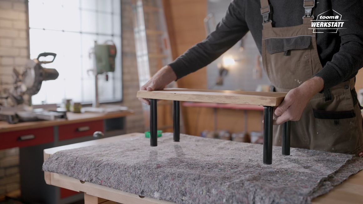 Person baut kleines Holzregal zusammen