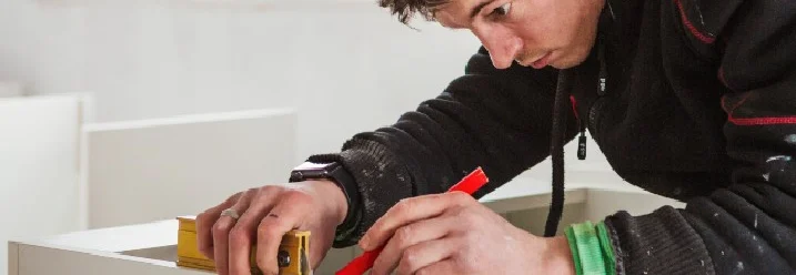 Person baut Möbelstück zusammen.