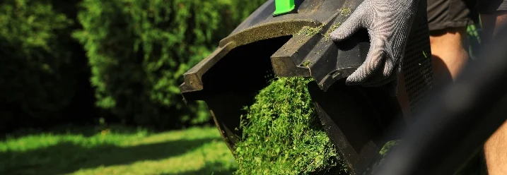 Person entleert Rasenmäher