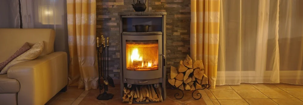 Ein Kaminofen brennt mit Kaminbesteck daneben.