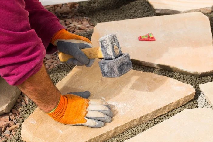 Person befestigt Steinplatte mit Hammer