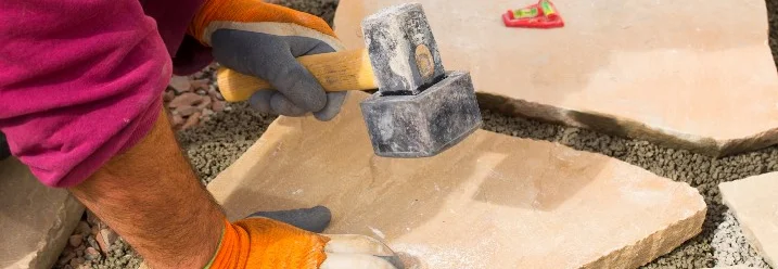 Person befestigt Steinplatte mit Hammer