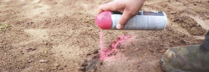 Person markiert den Boden mit Sprühfarbe