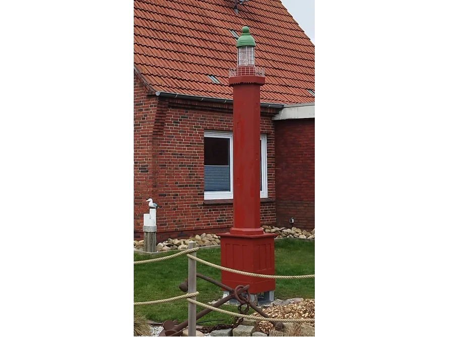 Roter Leuchtturm vor einem Haus