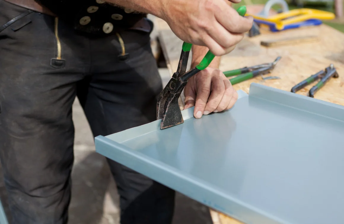 Person biegt Blech mit Zange