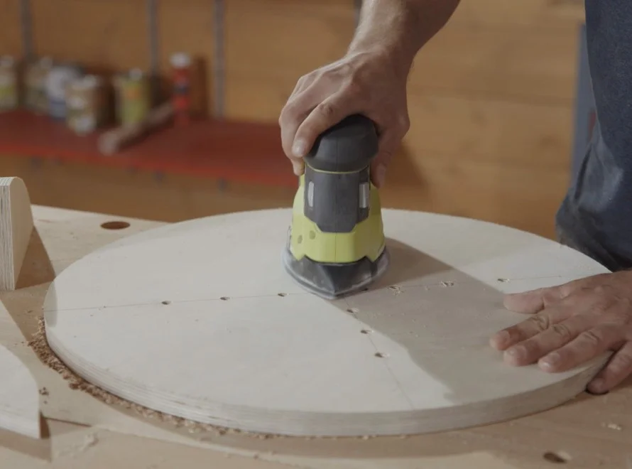 Person schleift eine runde Holzplatte
