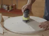 Person schleift eine runde Holzplatte
