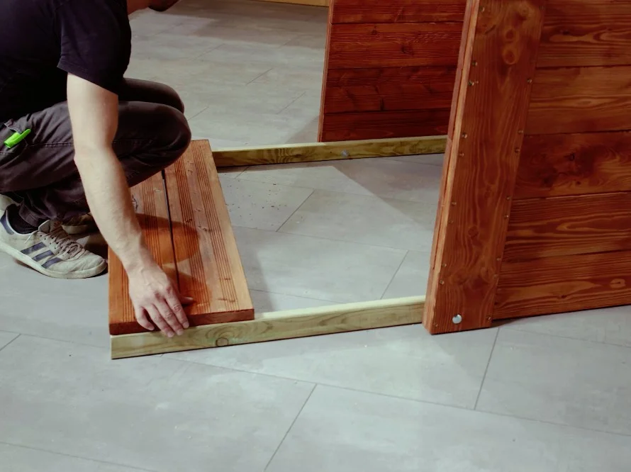 Person baut Holzrahmen zusammen