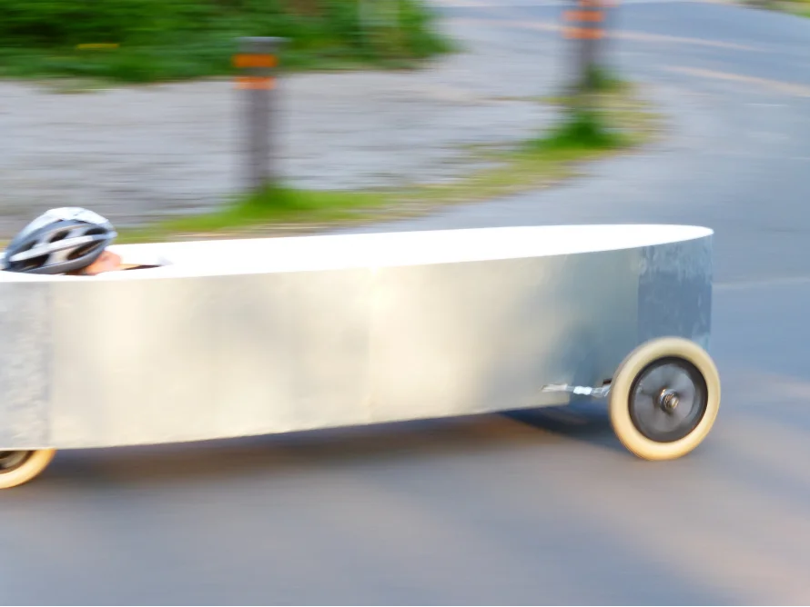 Person mit Helm in einem fahrenden, selbstgebauten Gefährt