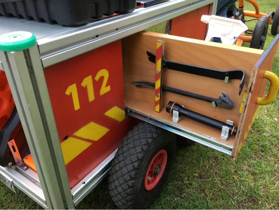 Roter Wagen mit offener Schublade, darin Werkzeug
