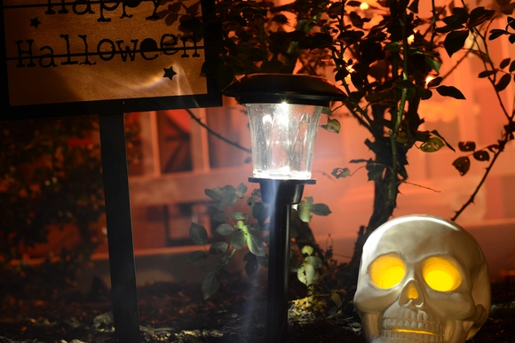Nächtliche Halloween-Dekoration mit leuchtendem Totenkopf, Solarlampe und Schild.