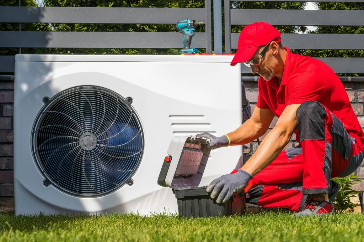 Person mit Werkzeugkoffer vor Wärmepumpe