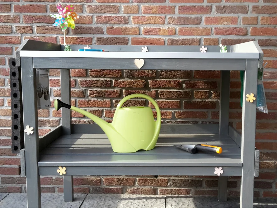 Grauer Tisch mit Gießkanne und Gartenwerkzeug