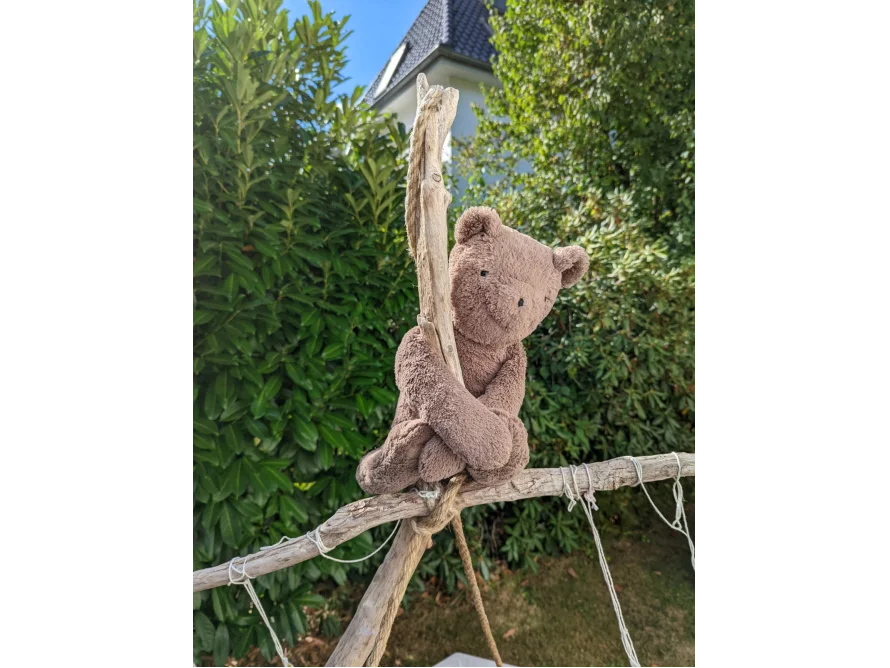 Teddybär klettert auf Holzgerüst