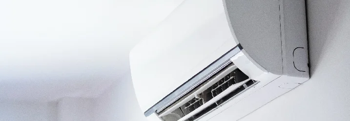 Ein weißes Klimagerät ist an einer weißen Wand befestigt.