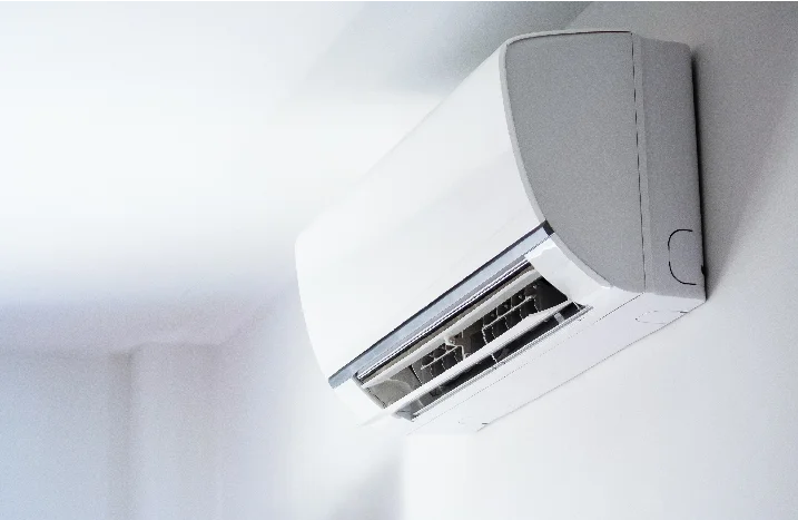 Ein weißes Klimagerät ist an einer weißen Wand befestigt.