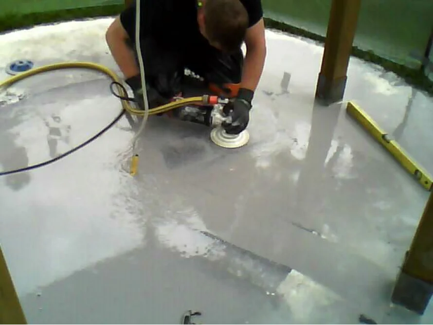 Person glättet Betonboden mit Schleifmaschine