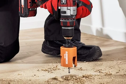 Person bohrt mit Akkuschrauber Loch in Holzboden