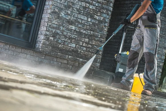 Person reinigt Terrasse mit Hochdruckreiniger