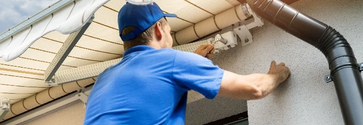 Person montiert Markise an Hauswand