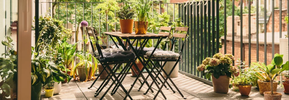 Sonniger Balkon mit vielen Pflanzen und Bistrotisch