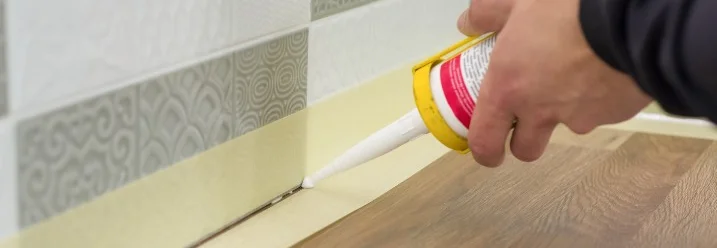 Person verwendet Dichtmittel in einer Küche