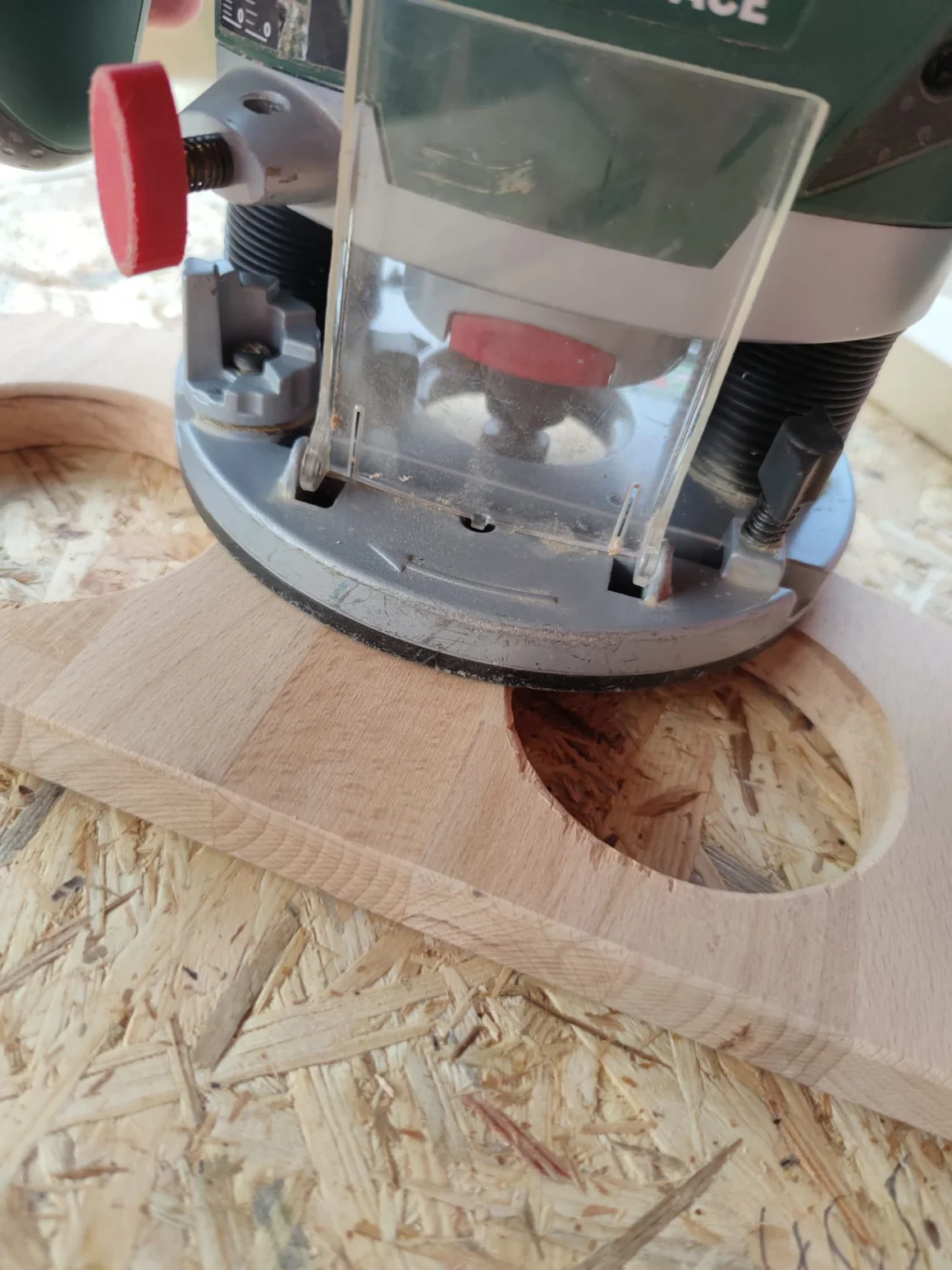 Eine Oberfräse fräst ein rundes Loch in eine Holzplatte.