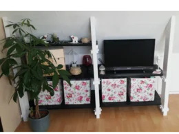 Ein weißes Regal mit einem Fernseher und Aufbewahrungsboxen.