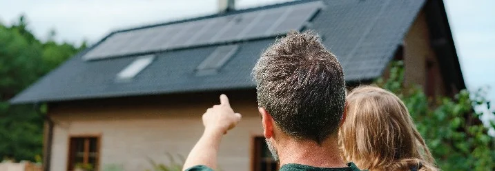 Person zeigt Kind Solaranlage auf Hausdach