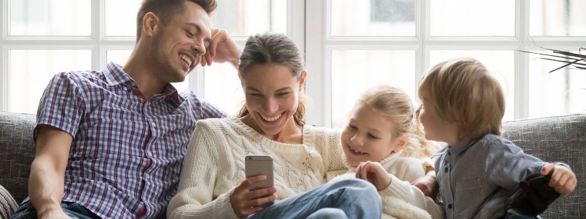 Eltern sitzen mit ihren zwei Kindern auf der Couch