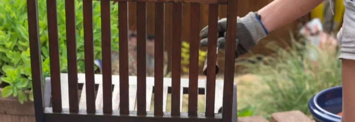 Person streicht einen Holzstuhl