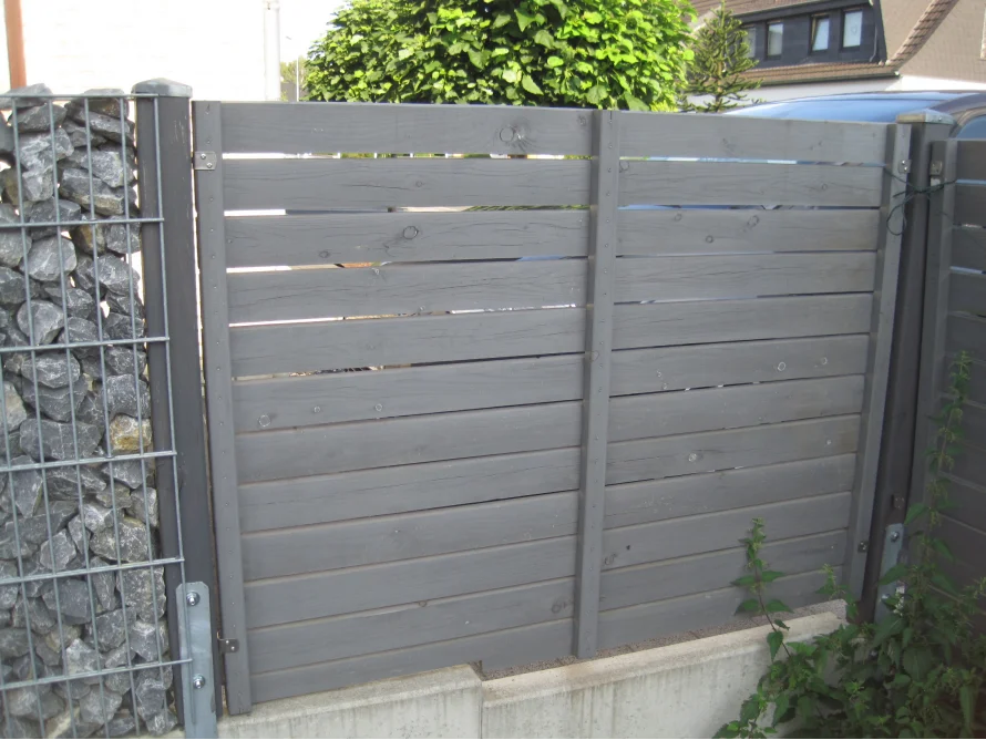 Grauer Holzzaun mit Gabionen