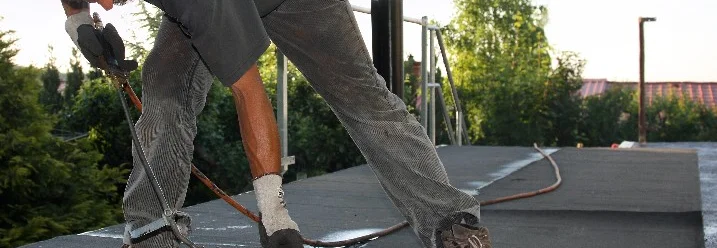 Person befestigt Dachpappe mit Brenner