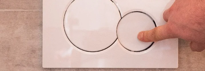 Hand drückt WC-Spültaste