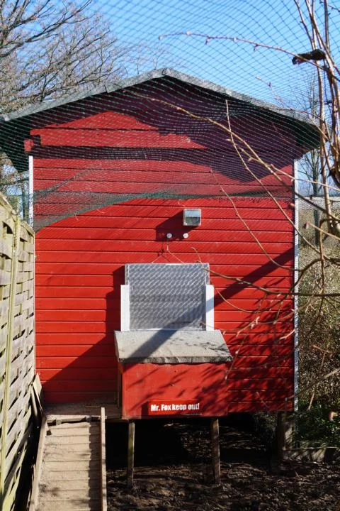 Rotes Gartenhaus mit Voliere