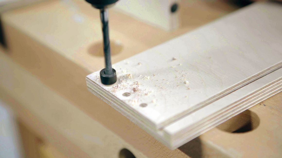 Mithilfe eines Stoppers werden Löcher in ein Holzstück gebohrt.