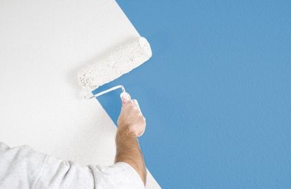Mann mit Farbrolle streicht Wand bunte Wand weiß