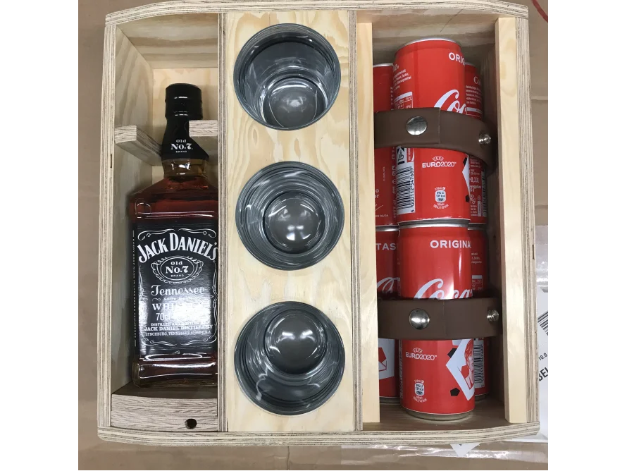 Ein Holzkasten mit einer Flasche und Dosengetränken sowie Gläsern.