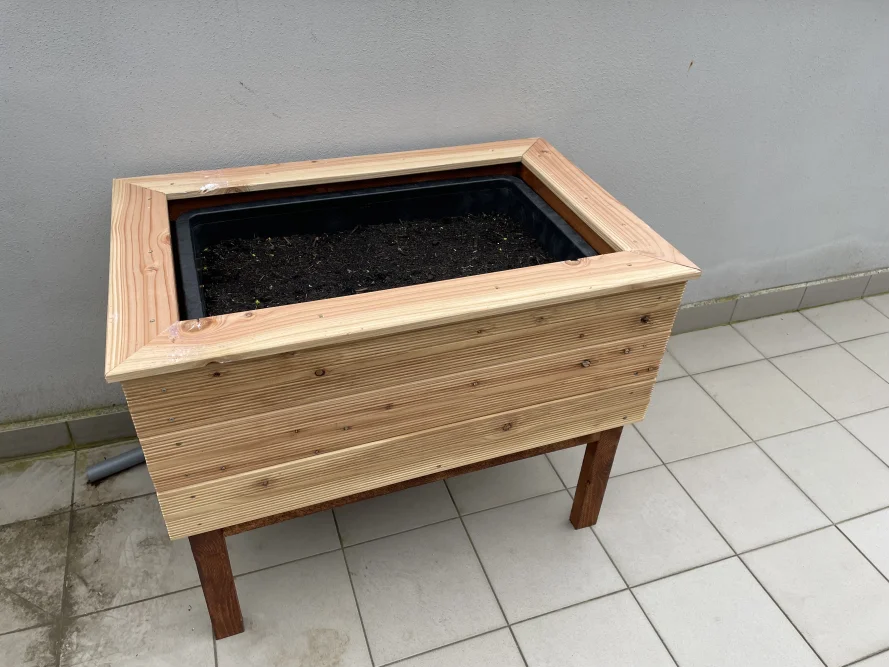 Holzbeet mit Erde auf Fliesenboden