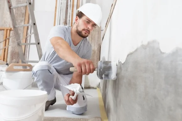 Person verputzt Wand mit Kelle
