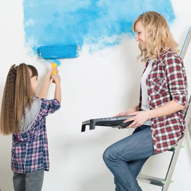 Zwei Personen streichen eine Wand blau.
