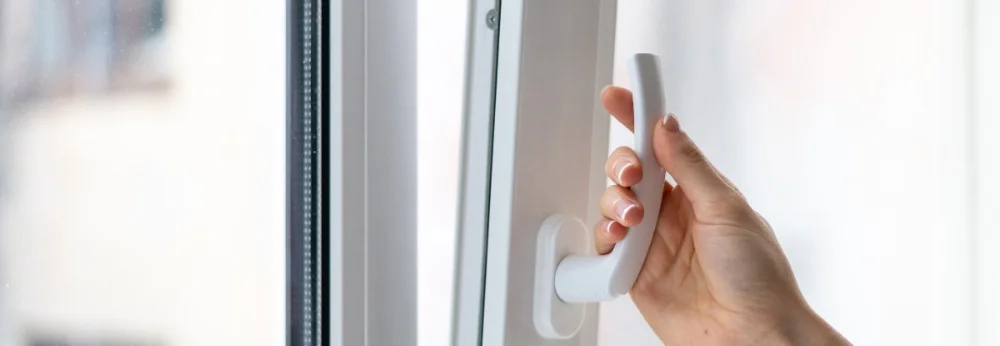 Hand öffnet Fenstergriff