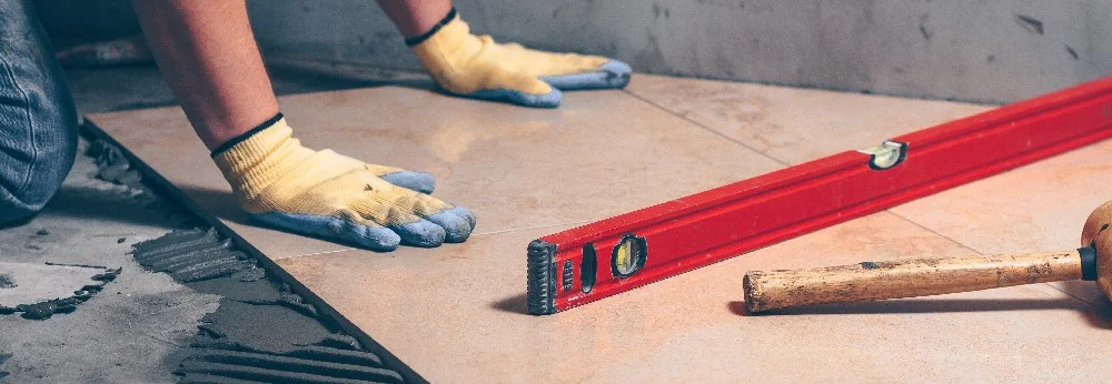 Person verlegt Fliesen mit Wasserwaage