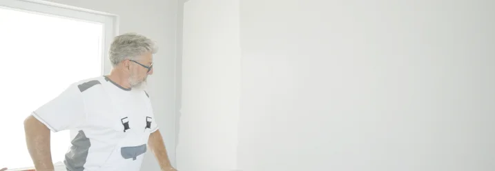 Person streicht Wand mit Farbrolle